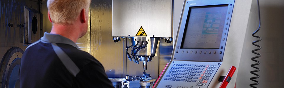 Der Facharbeiter gibt die Fertigungsdaten an der 5-Achs CNC-Fräsmaschine ein
