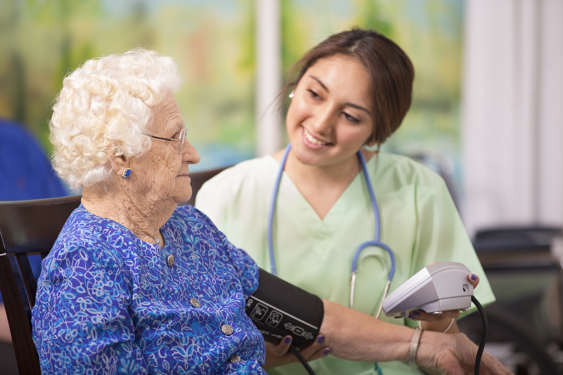 100 year old female patient gets exam from her Latin descent home healthcare nurse in nursing home or home setting.