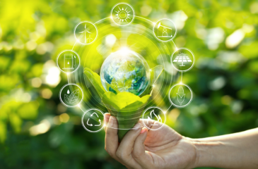 Eine Hand hält einen Strauß aus Blättern. In dessen Mitte ist eine 3D-Grafik der Erde zu sehen. Um die Erdkugel drehen sich 9 Symbole die für Energiequellen stehen. Ressourceneffizienz