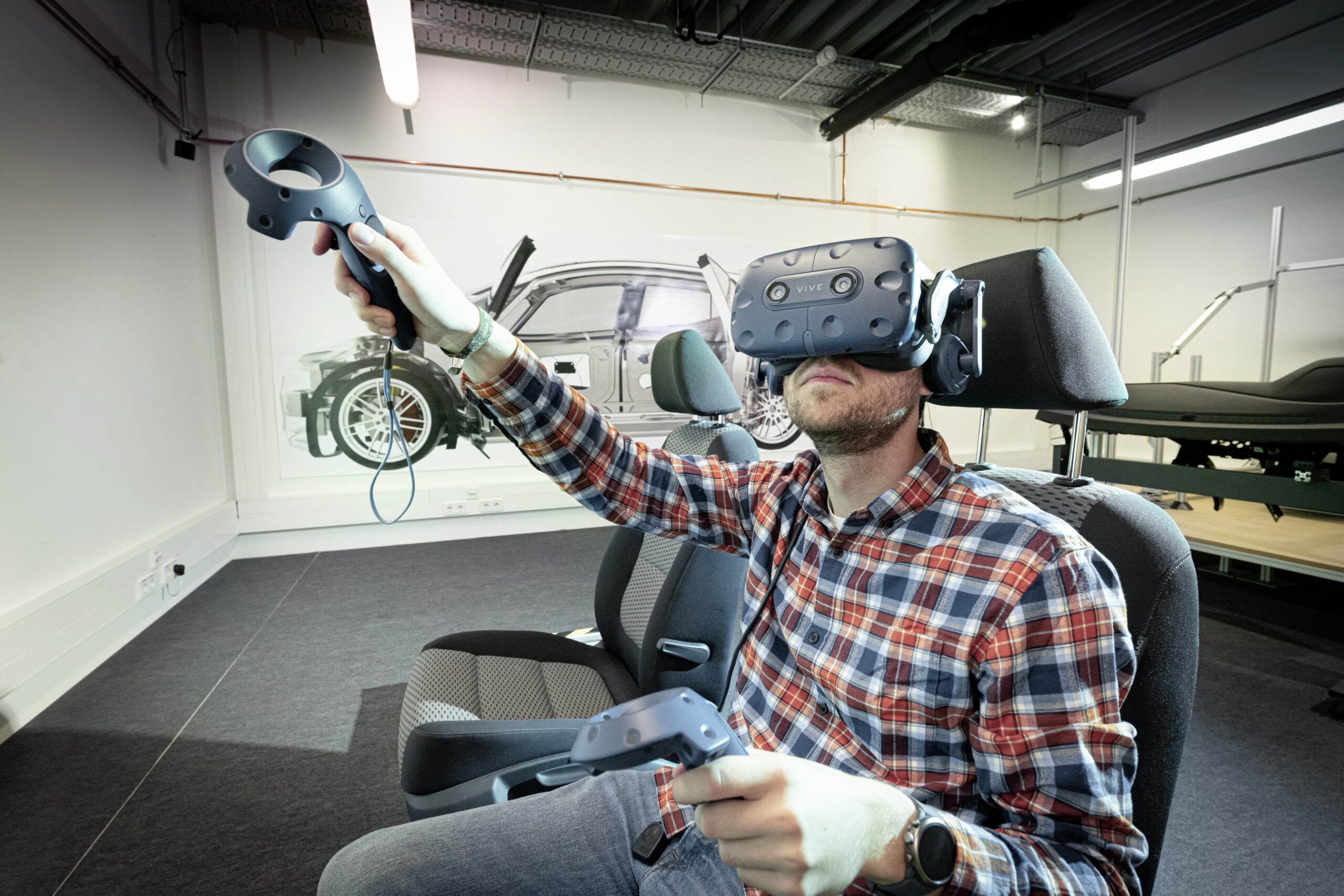 Ein Mann mit Virtual Reality-Brille sitzt in einem Fahrsimulator und bedient diesen. Virtuelle Realität