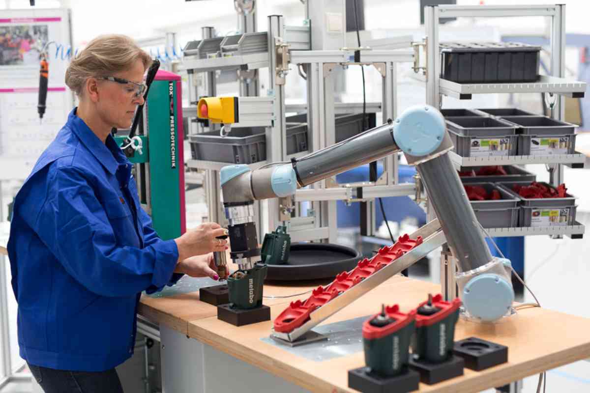 Kollaborative Bohrmaschinenmontage: eine Frau montiert in Zusammenarbeit mit einem Roboterarm eine Bohrmaschine.