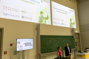 Zwei Vortragende bei der Abschlusskonferenz vor einer Tafel mit Projektionen über den Köpfen. Datenorientierte Wertschöpfung