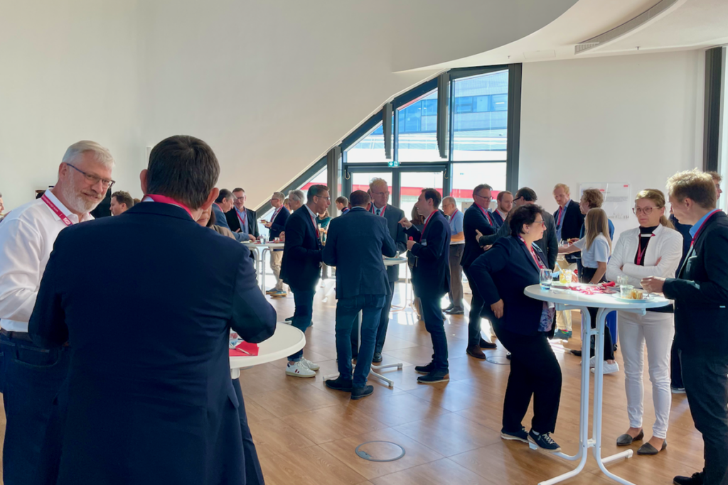 Stehtische an denen die Teilnehmer bei der Jahreskonferenz 2023 des Deutschen Forum Dienstleistungsforschung (DF)² Getränke und Snacks konsumieren während sie sich unterhalten.