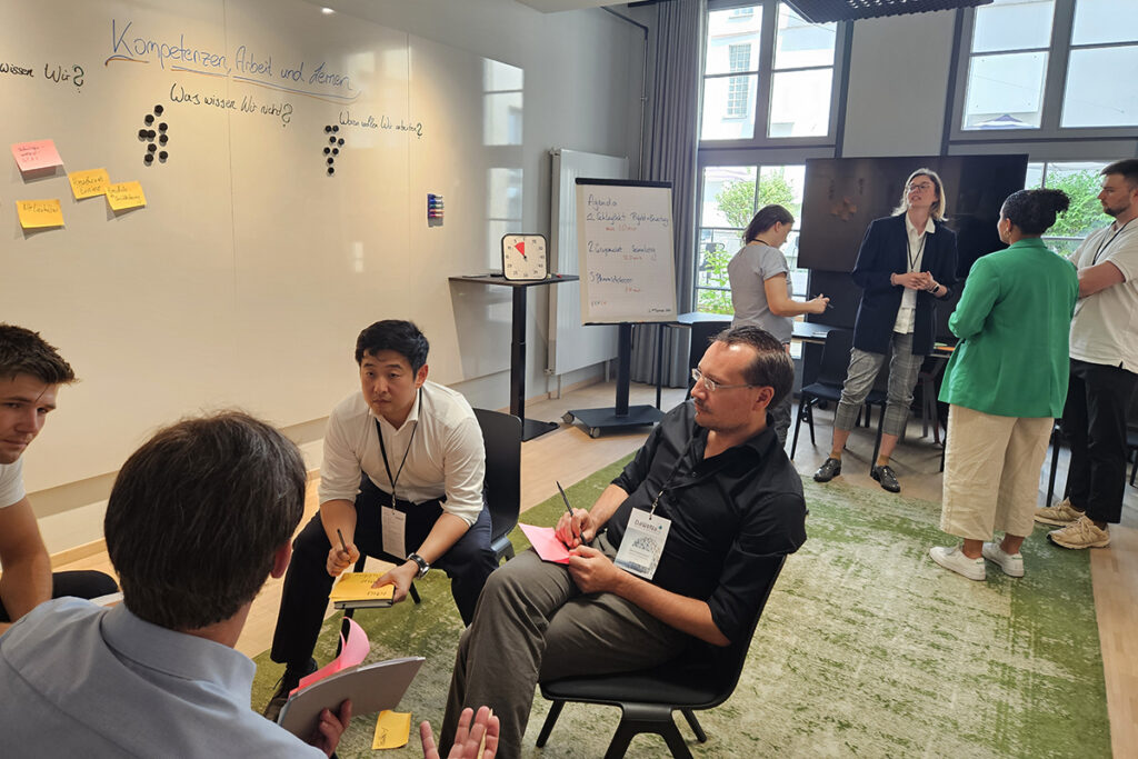 Austausch beim Kick-off des DaWeNa-HUB: Teilnehmende stehen und sitzen bei einem offenen Workshop-Format und diskutieren.