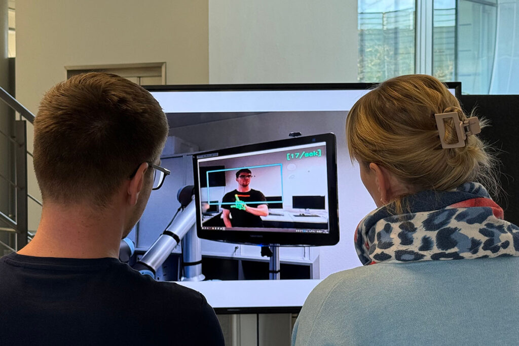 Ein Mann und eine Frau stehen vor einem Demonstrator bei der Abschlussveranstaltung der Projekte PraeRI und TeleInteraction-XR
