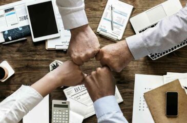 Bild der Bekanntmachung Arbeitshandeln für Kreativität, Innovation und resiliente Wertschöpfung (AKIRes). Vier Hände in einem Kreis zusammengeführt in einer Besprechungssituation: sie symbolisieren Teamwork, Kreativität und Innovation.